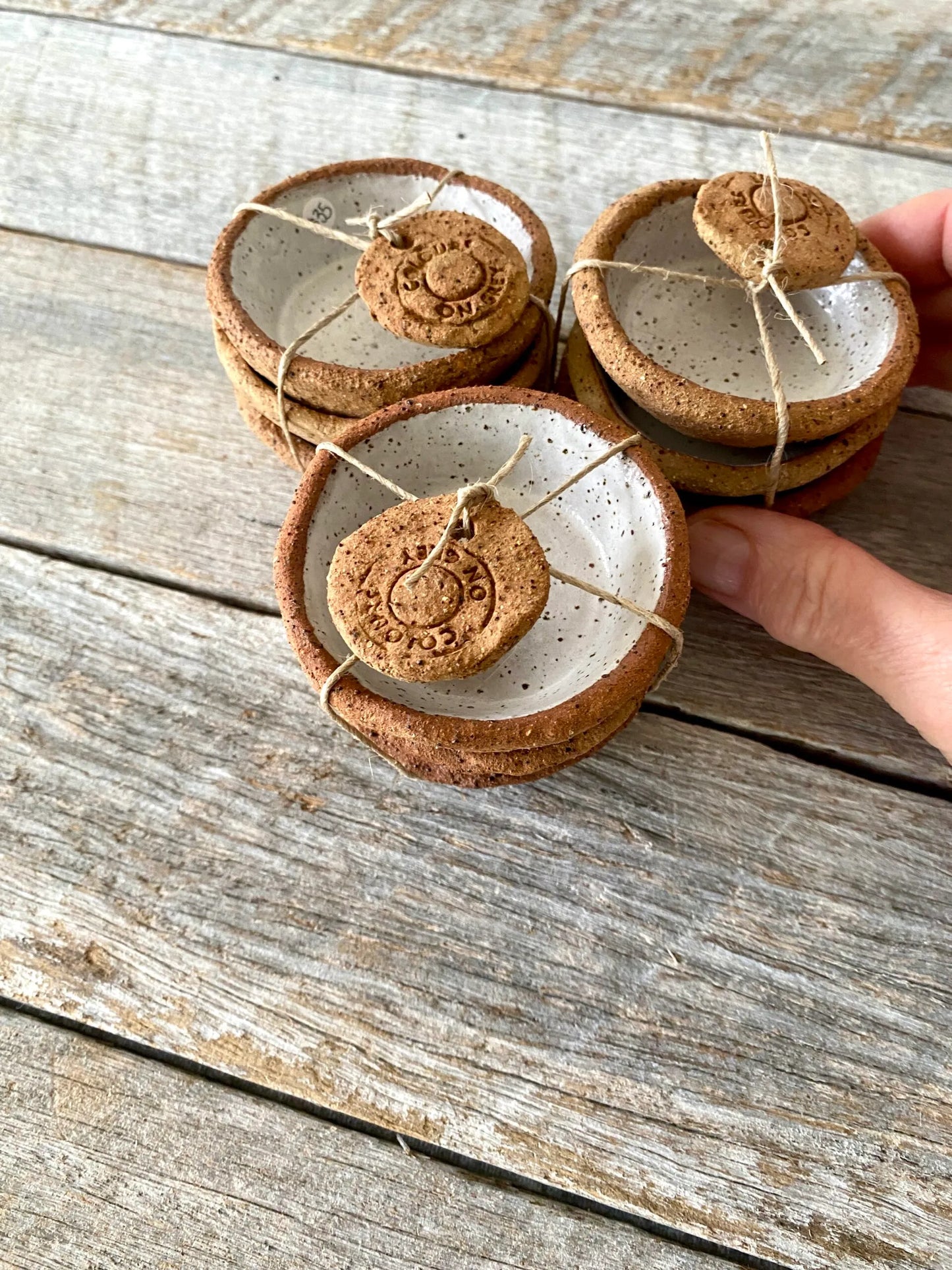 A set of 3 small hand formed trinket bowls. Rustic clay with speckled white glaze.  (6-01)